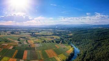 Vista panorámica de un paisaje rural con campos, un río y colinas boscosas.