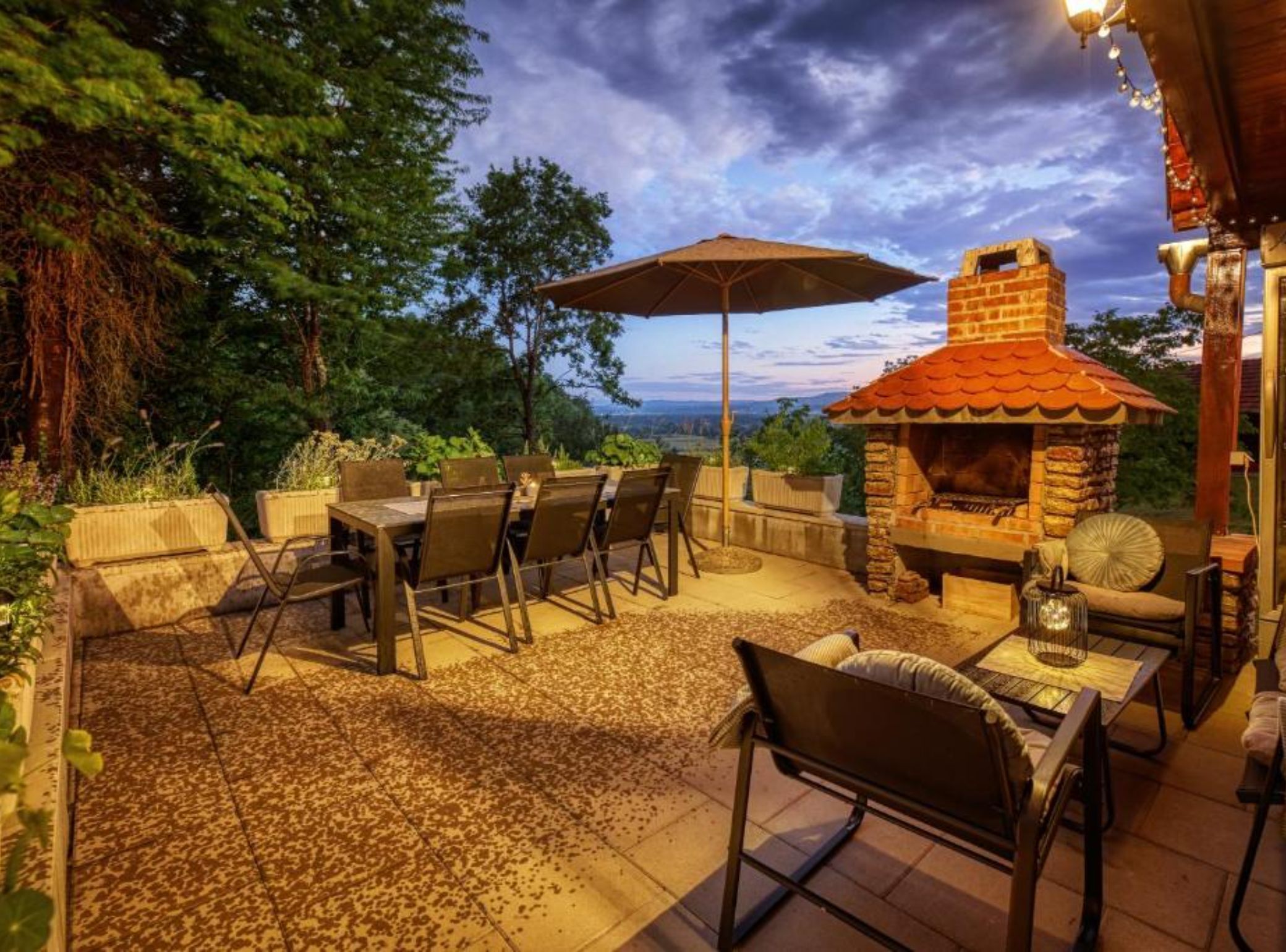 An outdoor patio with a brick fireplace, outdoor seating, and a view of the landscape.