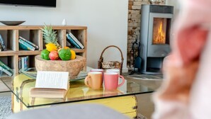 A cozy living room with a glass coffee table, a bowl of fruit, a book, and two mugs. - 2 Bed in West Putford (oc-u45226) (Sessacott)