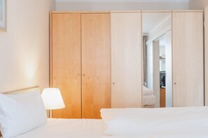 A hotel room with a bed, a nightstand, a lamp, and a wardrobe. - Ferienwohnung Strandnah in Sellin mit Balkon und Wlan (Sellin)