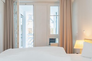 A hotel room with a large bed, a desk, a lamp, and a view of the outside. - Ferienwohnung Strandnah in Sellin mit Balkon und Wlan (Sellin)