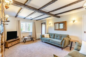 A living room with exposed wooden beams, a television, a sofa, and a small table. - 2 Bed in Carhampton (oc-v42711) (Carhampton)