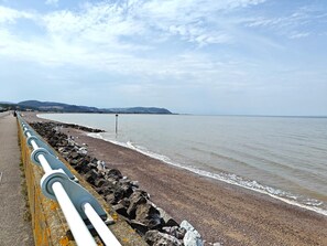 A coastal walkway with a rocky barrier, a clear sky, and distant hills. - 2 Bed in Carhampton (oc-v42711) (Carhampton)