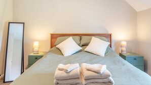A neatly made bed with pillows, two bedside lamps, and a stack of towels on the floor. - 2 Bed in Carhampton (oc-v42711) (Carhampton)