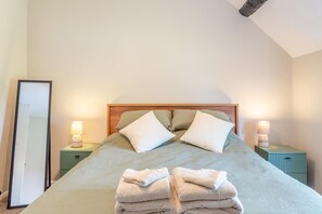 A neatly made bed with pillows, two bedside lamps, and a stack of towels on the floor. - 2 Bed in Carhampton (oc-v42711) (Carhampton)