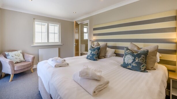 A hotel room with a large bed, bedside tables, a chair, and a window. - 2 Bed in Old Hunstanton (oc-b44902) (Hunstanton)