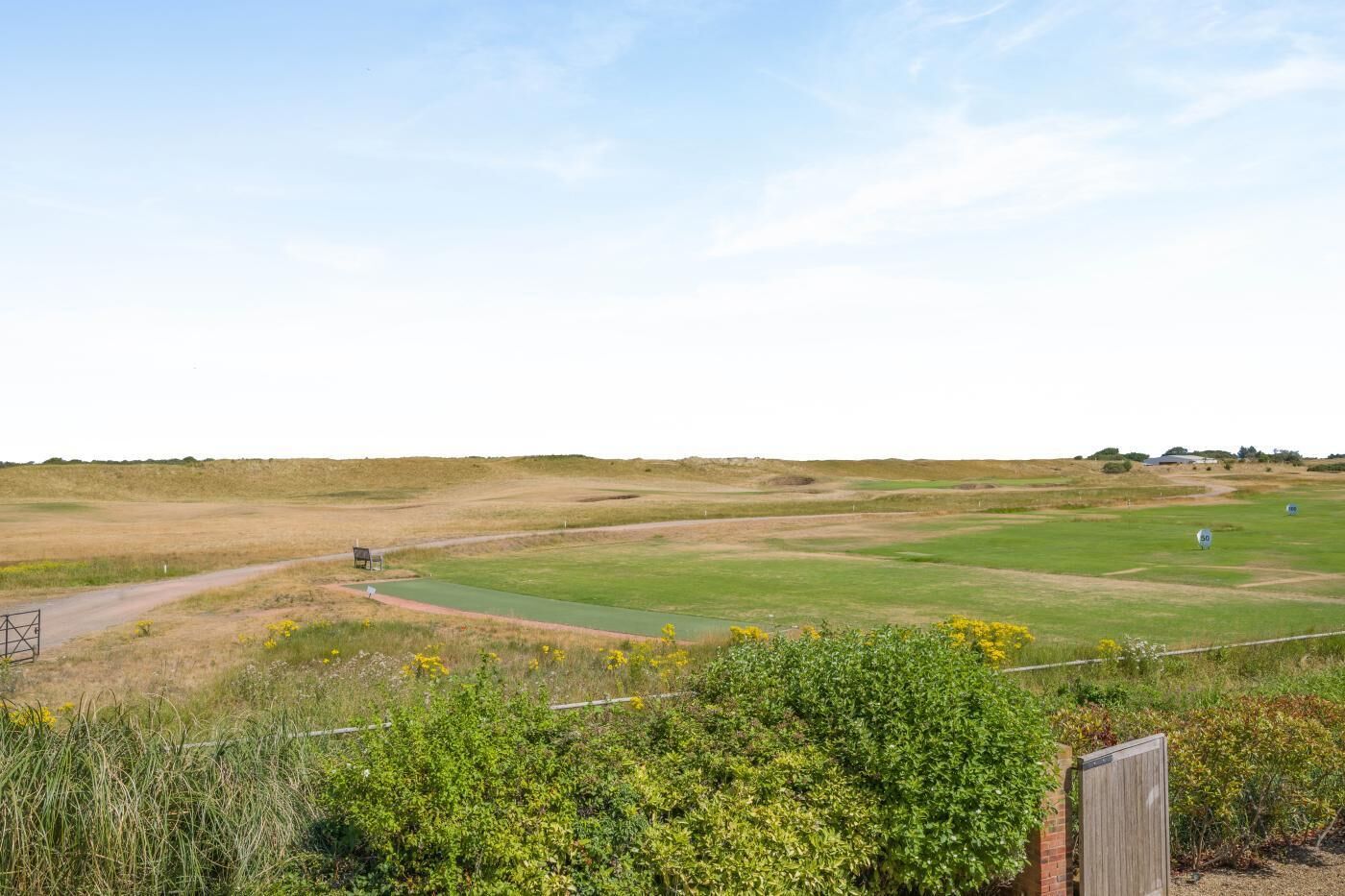 A golf course with a clear sky, a green fairway, and a water hazard.