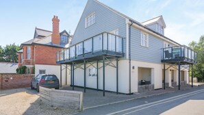 A two-story residential building with a balcony, a garage, and a driveway. - 2 Bed in Old Hunstanton (oc-b44902) (Hunstanton)