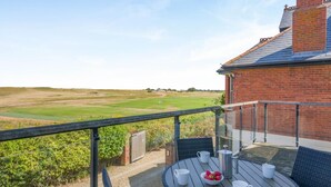 A balcony with a table, chairs, and a view of a golf course. - 2 Bed in Old Hunstanton (oc-b44902) (Hunstanton)