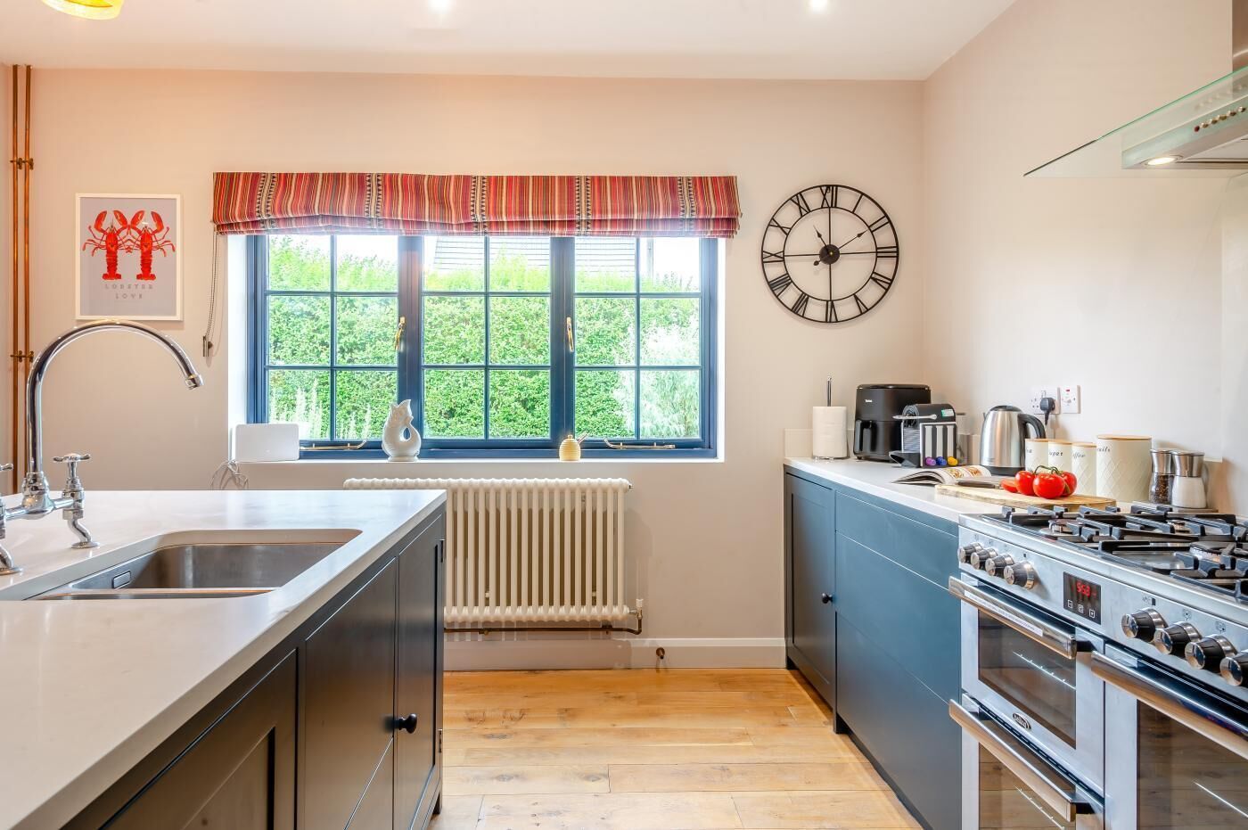 A modern kitchen with a large window, a clock, and a stove.