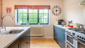 Eine moderne Küche mit großem Fenster, einer Uhr und einem Herd.