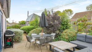 Eine Terrasse im Freien mit Tisch, Stühlen, einem Grill und einer Couch.