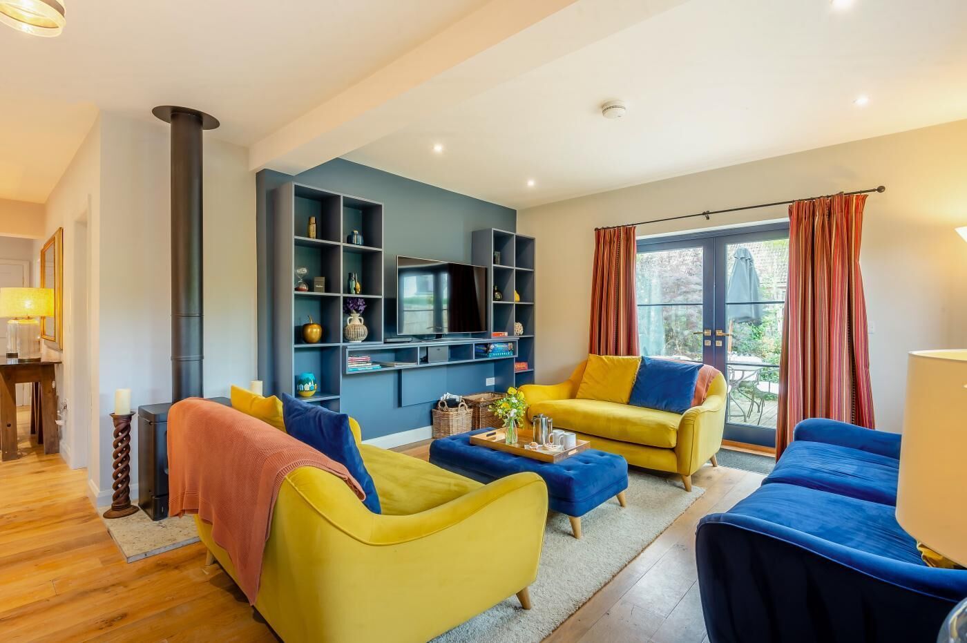 A modern living room with a sofa, ottoman, and a flat-screen TV on a wall.
