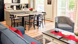 Una cocina moderna con comedor, una sala de estar con sofá y un balcón con una silla.
