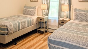 Un dormitorio con dos camas, una ventana con cortinas, mesitas de noche con lámparas y decoración en la pared.