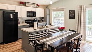 Una cocina moderna con un refrigerador negro, un microondas y una estufa. Hay una zona de comedor con una mesa y sillas.