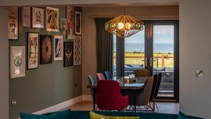 Ein Essbereich mit Tisch, Stühlen und Meerblick durch ein großes Fenster.