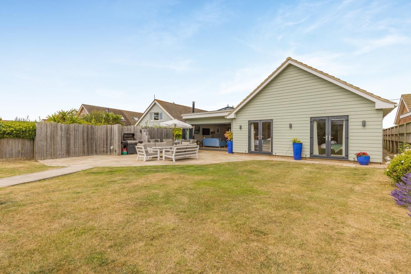 A residential property with a fenced backyard, outdoor seating area, and a garage.