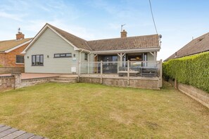 A residential property with a covered patio, a brick exterior, and a well-maintained lawn. - 4 Bed in Hunstanton (oc-o44907) (Hunstanton)