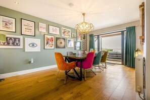 A dining area with a wooden table, colorful chairs, and a chandelier. - 4 Bed in Old Hunstanton (oc-o44907) (Hunstanton)