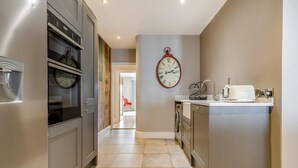 Een moderne keuken met roestvrijstalen apparatuur, een centraal eiland met een spoelbak en een klok aan de muur.