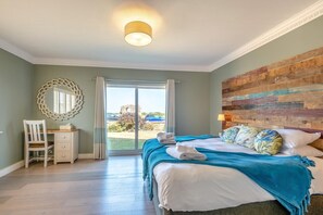 A hotel room with a bed, a desk, a chair, a large mirror, and a view of the outside. - 4 Bed in Hunstanton (oc-o44908) (Hunstanton)