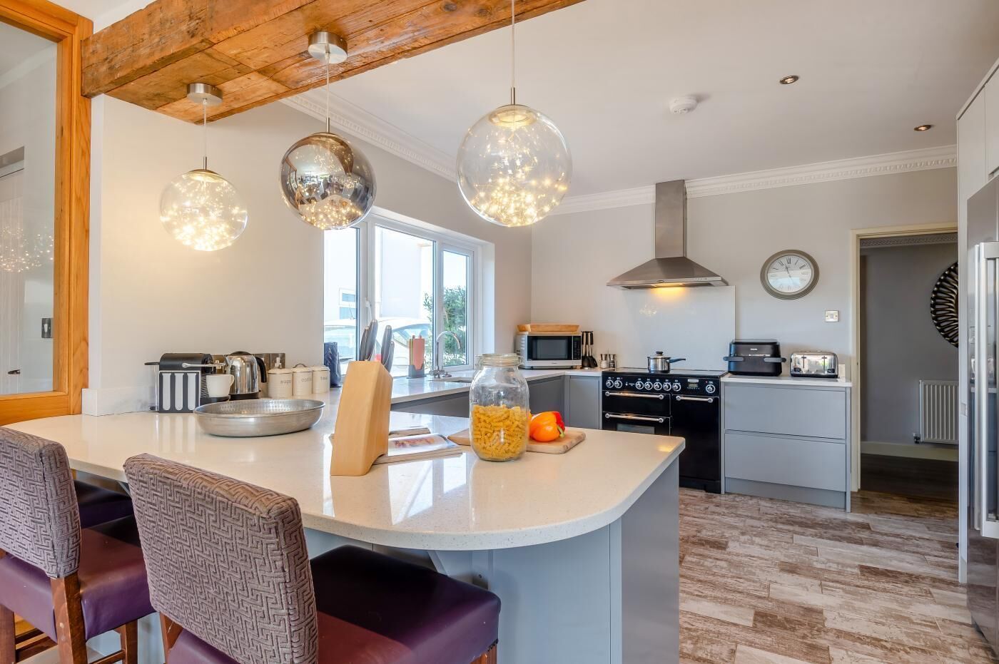 Een moderne keuken met een centraal eiland, hanglampen en uitzicht naar buiten.