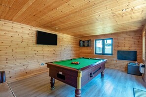A wooden-paneled room with a pool table, a dartboard, and a window. - 4 Bed in Hunstanton (oc-o44908) (Hunstanton)