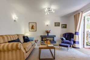 Ein Wohnzimmer mit einer Couch, Sesseln, einem Couchtisch, einem Kamin und Kunstwerken an den Wänden.