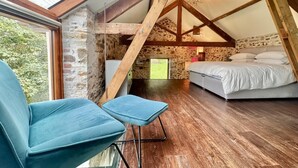 A bedroom with a sloped ceiling, a bed, a chair, and a view through a window. - 2 Bed in Milton Damerel (oc-s42659) (Milton Damerel)