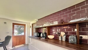 A kitchen with a brick backsplash, a microwave, a toaster, and a coffee maker. - 2 Bed in Milton Damerel (oc-s42659) (Milton Damerel)