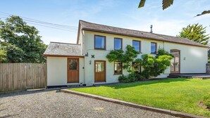Une maison à deux étages avec un jardin devant, une clôture en bois et une allée gravillonnée.