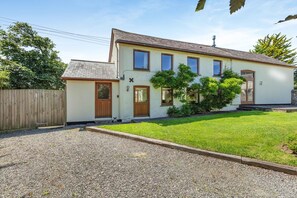 Ein zweistöckiges Haus mit Vorgarten, Holzzaun und Schotterauffahrt.
