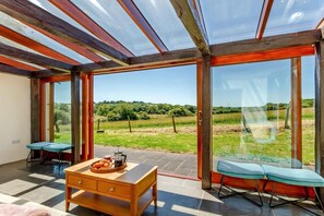 Ein Zimmer mit einer großen Glasdoor, einem Holztisch mit einer Auswahl an Gebäck und zwei Stühlen.