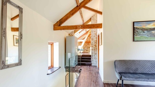 Un intérieur moderne avec un escalier en bois, une rambarde en verre et un banc.