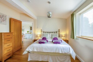 Ein Schlafzimmer mit Bett, Nachttischen, einem Kleiderschrank, einer Pendelleuchte und einem Fenster mit Vorhängen.