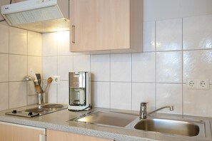 A kitchen with a coffee maker, a sink, and a range hood. - Strandnahe Ferienwohnung in Sellin mit Balkon (Sellin)