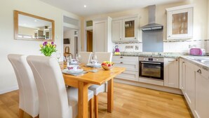 Een moderne keuken met witte kastjes, een houten eettafel en een inbouwoven.