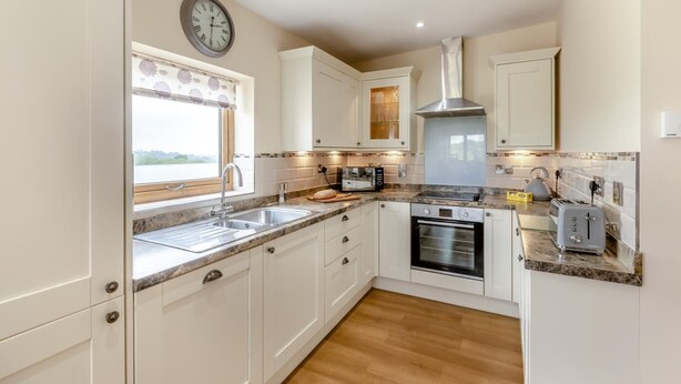 A modern kitchen with white cabinets, a built-in oven, a microwave, and a sink. - 3 Bed in Dalwood (oc-c42675) (Dalwood)