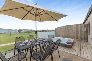 Eine Terrasse im Freien mit einem für Tee gedeckten Tisch, einem Whirlpool und einem großen Sonnenschirm.