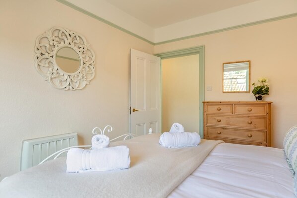 A hotel room with a bed, a dresser, a mirror, and a door.