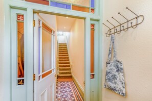 A hallway with a patterned floor, a staircase, and a wall-mounted coat rack.
