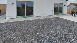 Un bâtiment moderne doté d’un toit plat, de grandes portes vitrées et d’une allée gravillonnée.
