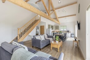 A spacious living area with a staircase, a dining table, and a kitchen in the background. - 3 Bed in Meidrim (oc-c45350) (Meidrim)