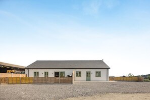 Un bâtiment d’un seul étage, doté d’un toit plat, d’une allée en gravier et d’une clôture en bois.
