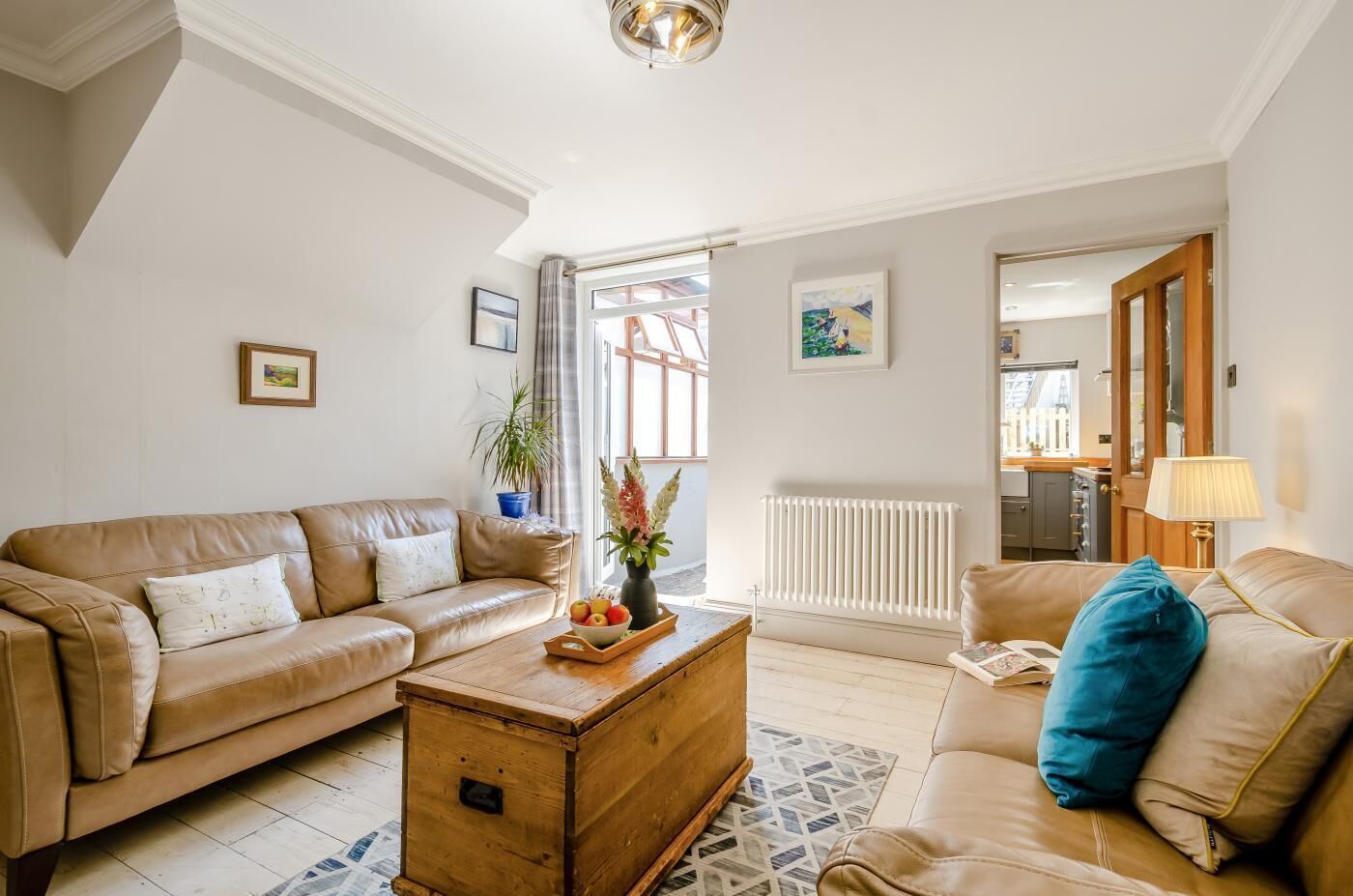 A living room with a beige sofa, a wooden coffee table, and a radiator.
