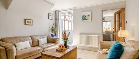 A living room with a beige sofa, a wooden coffee table, and a radiator.