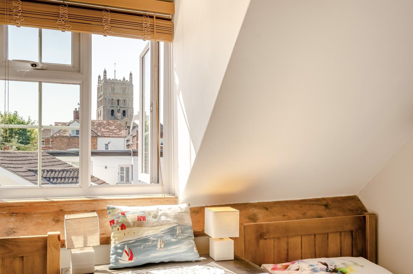 A bedroom with a large window, wooden headboard, and a view of a historic building.