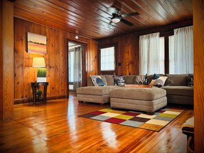 Una stanza con rivestimento in legno, un divano componibile, una lampada e un tappeto colorato.