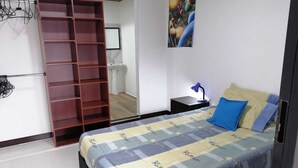 Une chambre à coucher avec un lit, une armoire, une table de chevet, une lampe et un tableau au mur.
